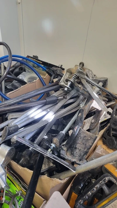 A box containing used bicycle kickstands and various spare parts.